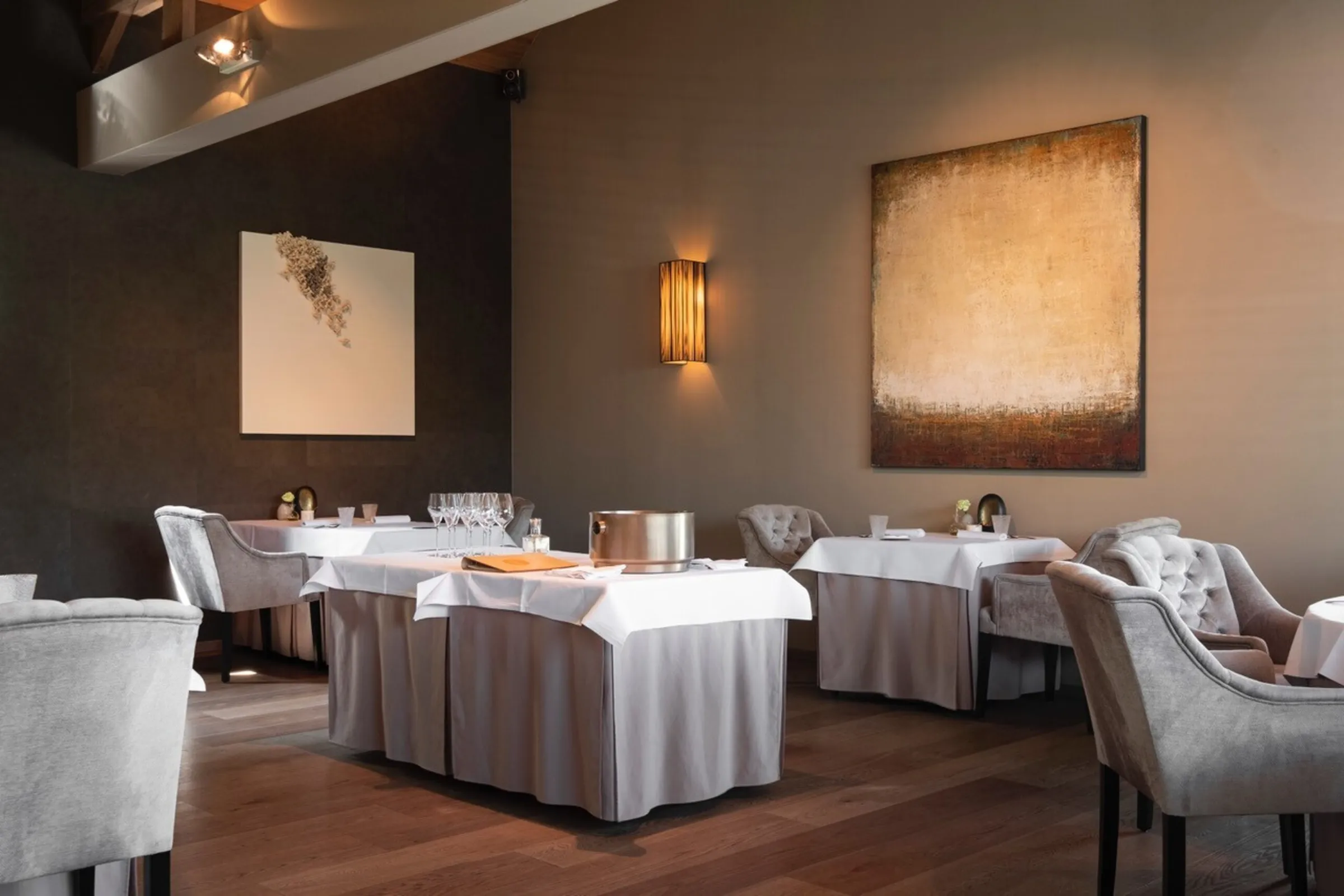 De zaal van La Belle met warme wandlampen en wit gedekte tafels